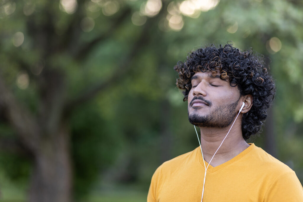 young man with dark hair wearing yellow shirt taking a deep breath