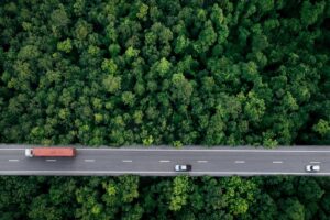 cars and a truck on a highway that is surrounded by trees
